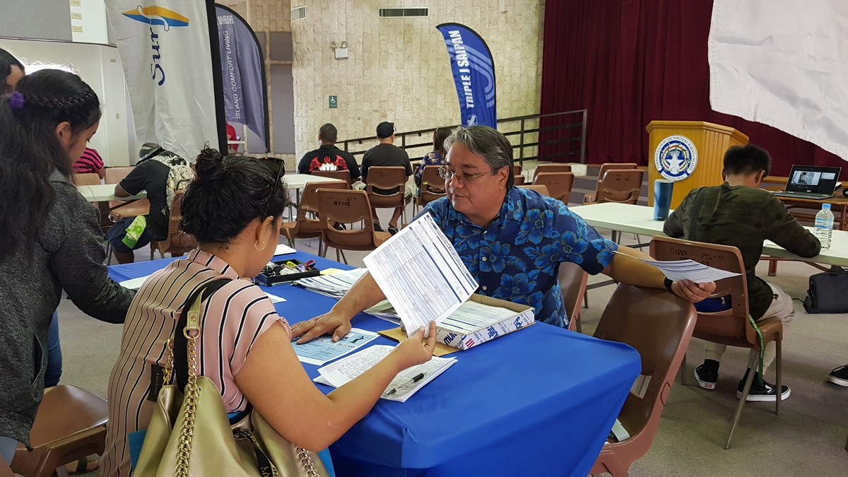 Triple J Saipan Human Resources director Frank Ada, right, assists applicants during the Triple J job fair at the multi-purpose center on Monday.