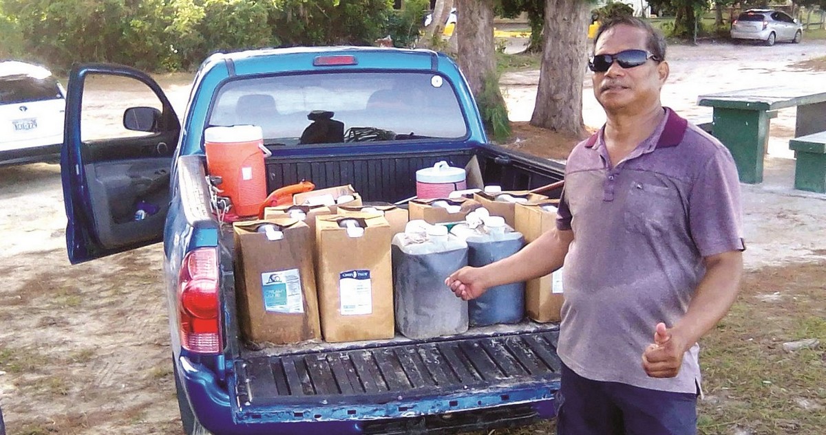 Community volunteer Max Aguon shows the containers of used cooking oil dumped at Sugar Dock Beach. Contributed photo