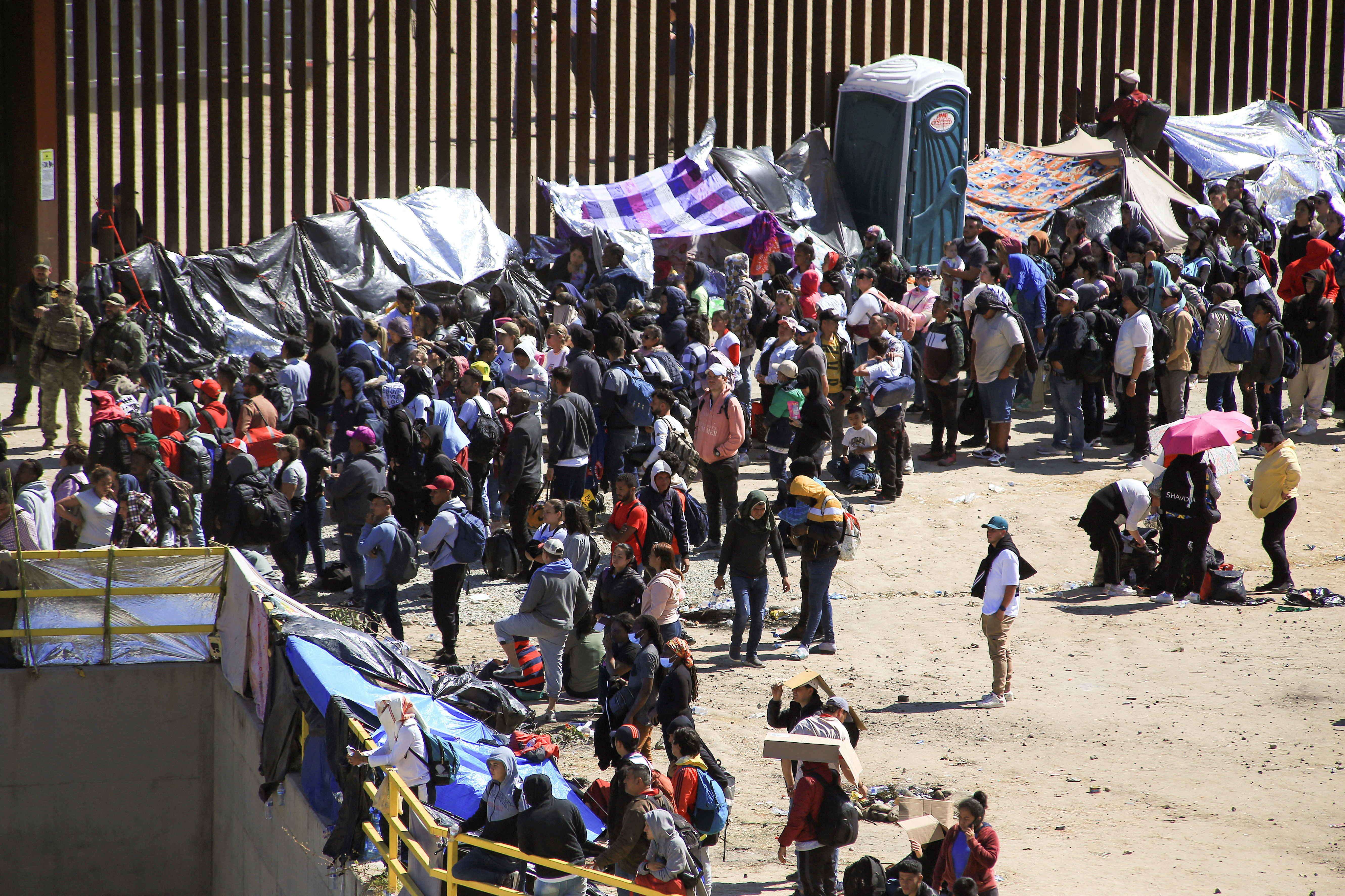 FILE PHOTO: Migrants gather between the primary and secondary border fences in San Diego as the United States prepares to lift COVID-19 era restrictions known as Title 42, that have blocked migrants at the U.S.- Mexico border from seeking asylum since 2020, as seen from Tijuana, Mexico May 8, 2023. REUTERS/Aimee Melo/File Photo