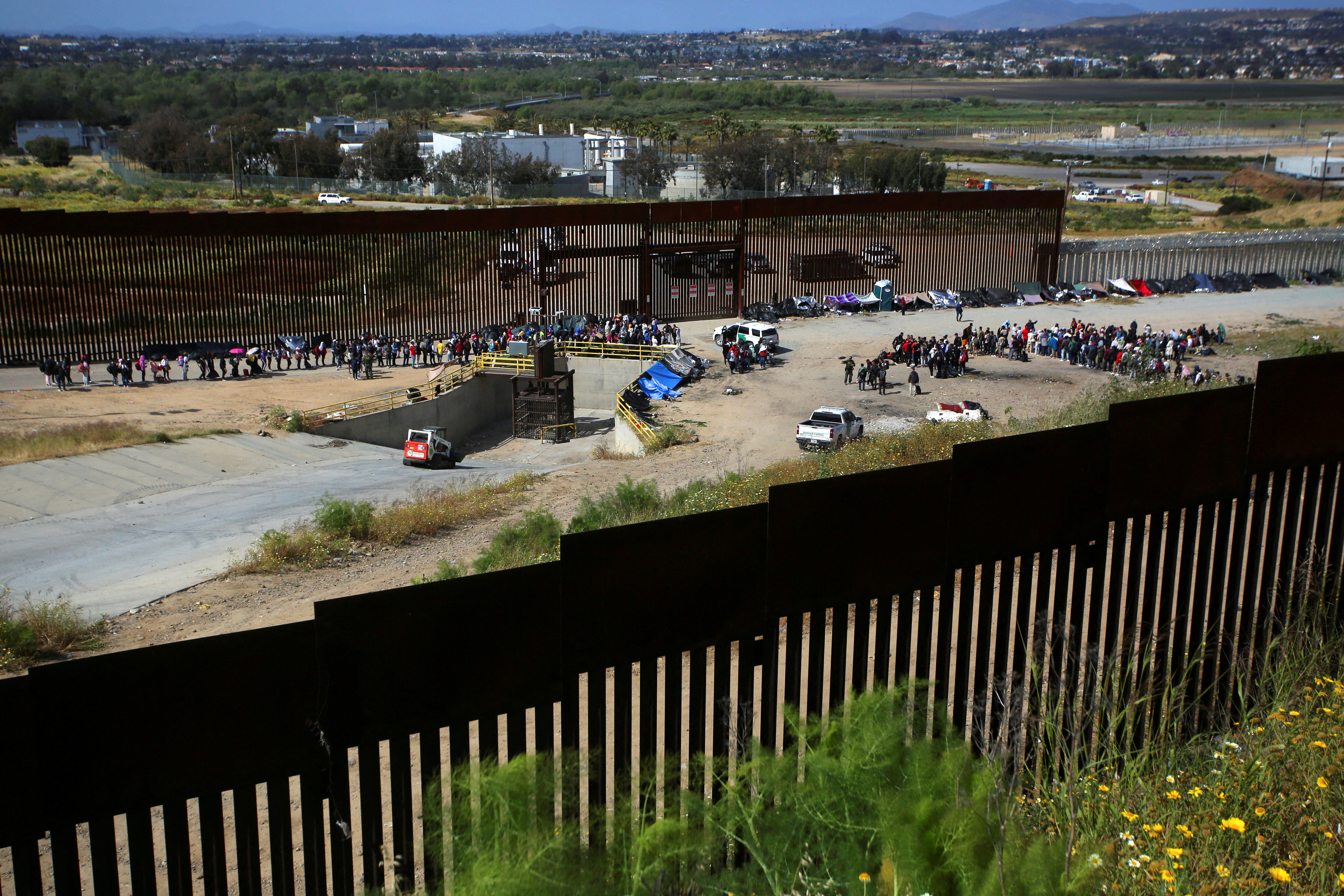 FILE PHOTO: Migrants gather between the primary and secondary border fences in San Diego as the United States prepares to lift COVID-19-era restrictions known as Title 42, that have blocked migrants at the U.S.- Mexico border from seeking asylum since 2020, as seen from Tijuana, Mexico May 8, 2023. REUTERS/Jorge Duenes/File Photo