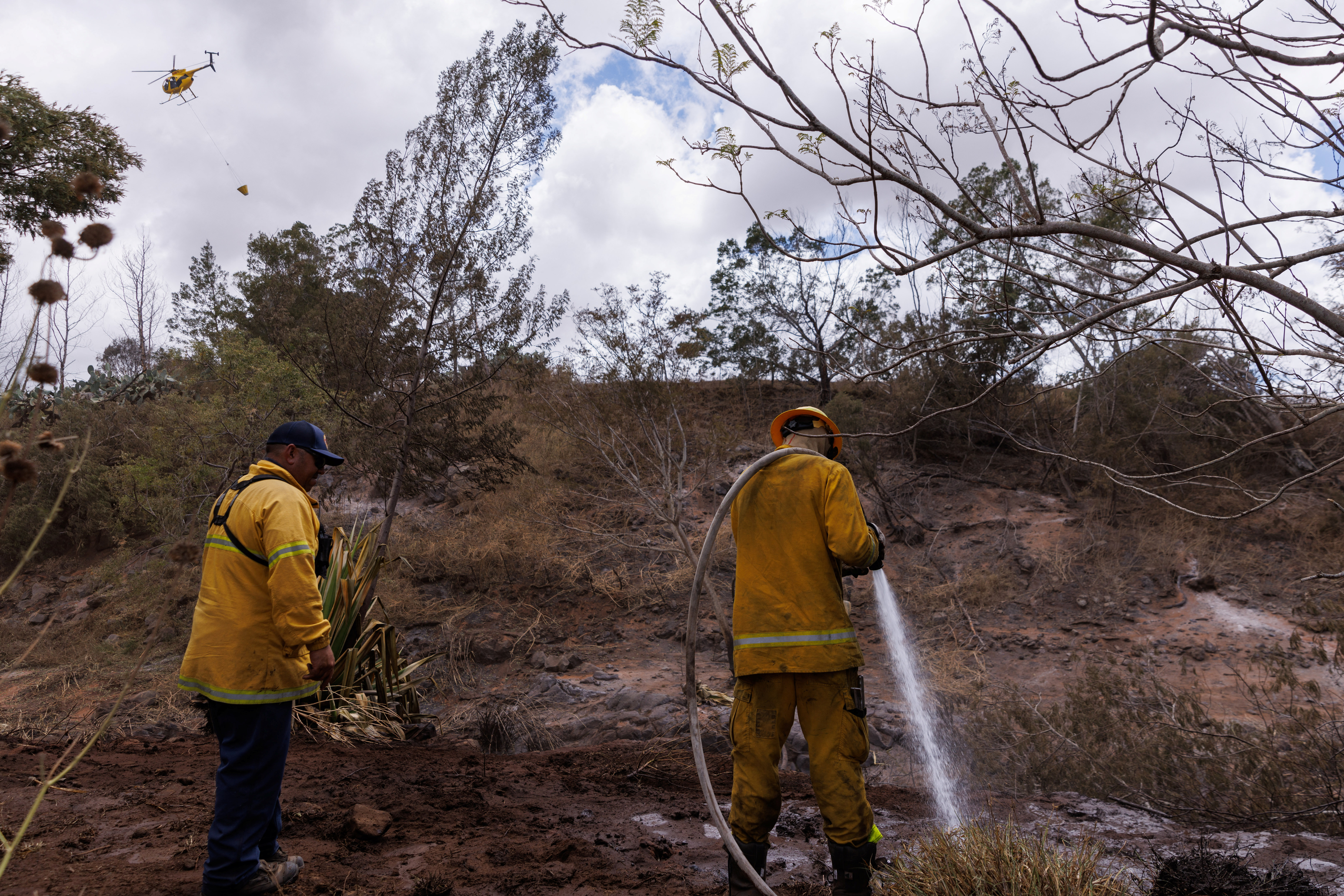 Maui County firefighters fight flare-up fires in a canyon in Kula on Maui island, Hawaii, U.S., August 13, 2023. REUTERS/Mike Blake