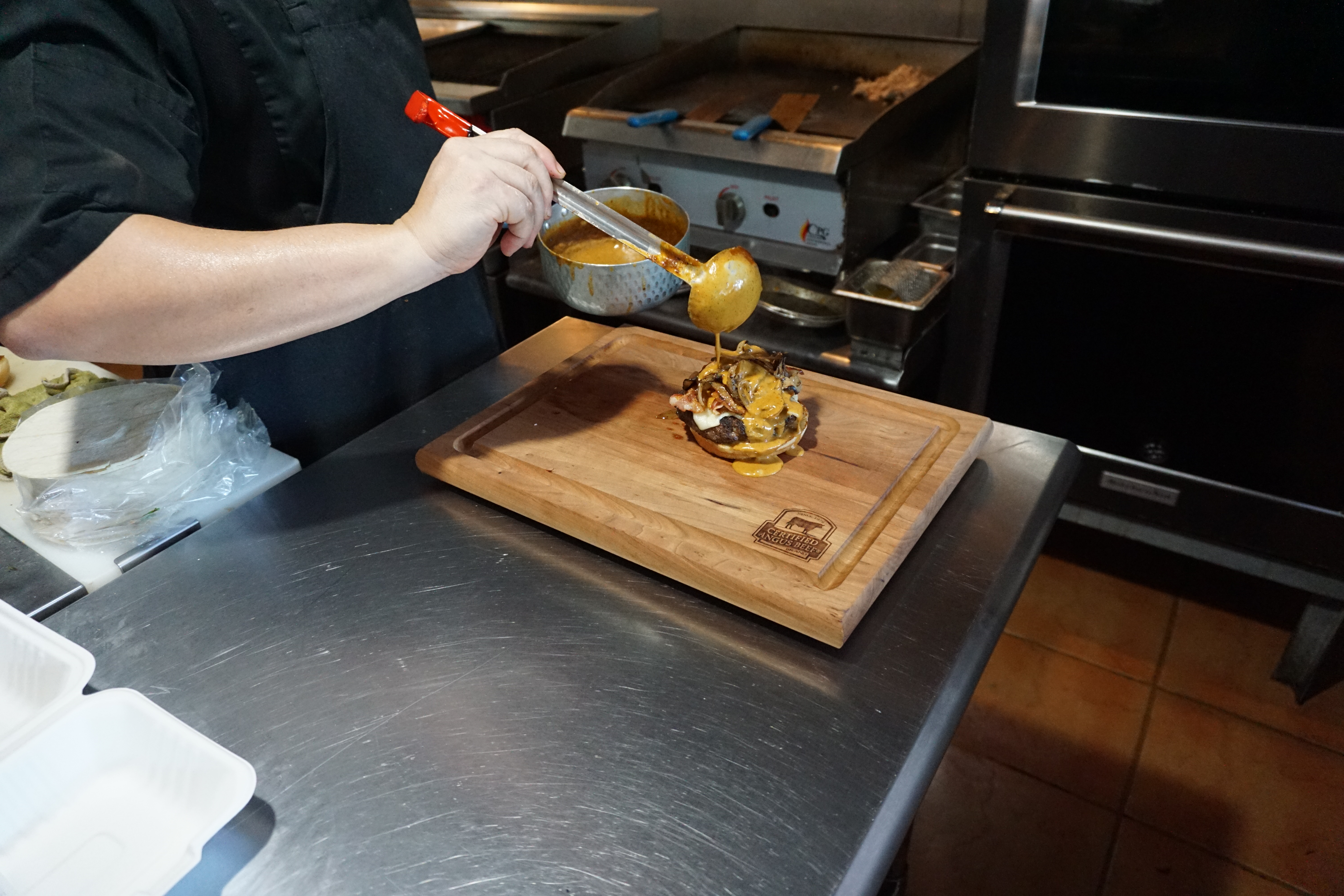 Chef Sonny layers on some beautifully flavorful ancho gravy onto the Kåksaka Burger at Ina's Kitchen