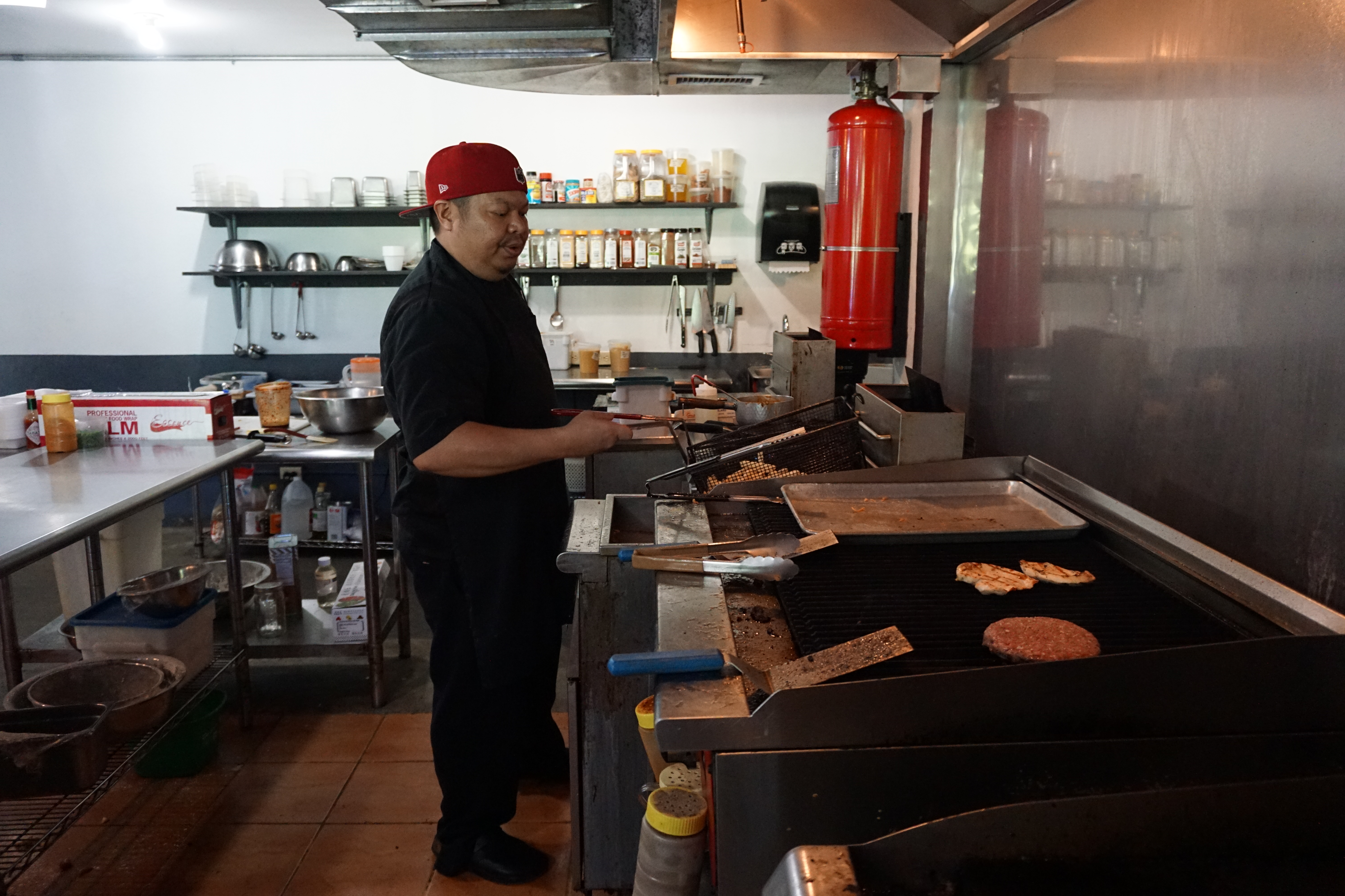 Chef/Owner of Ina's Kitchen, Sonny Sablan hard at work grilling a Kåksaka Burger to perfection.