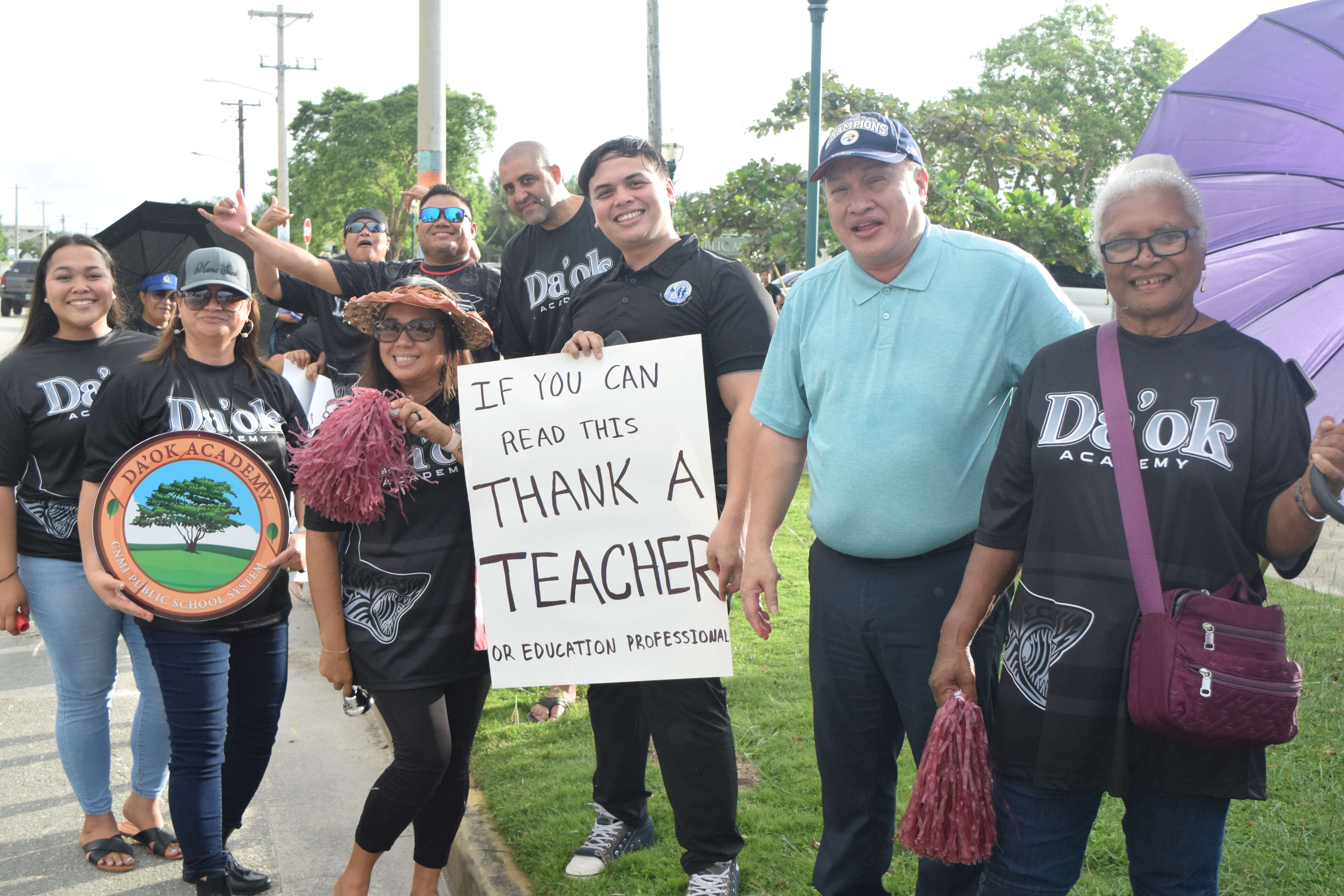 Board of Education member Andrew Orsini, second right, with Public School System staff during a roadside waving activity at Garapan Fishing Base on Monday.