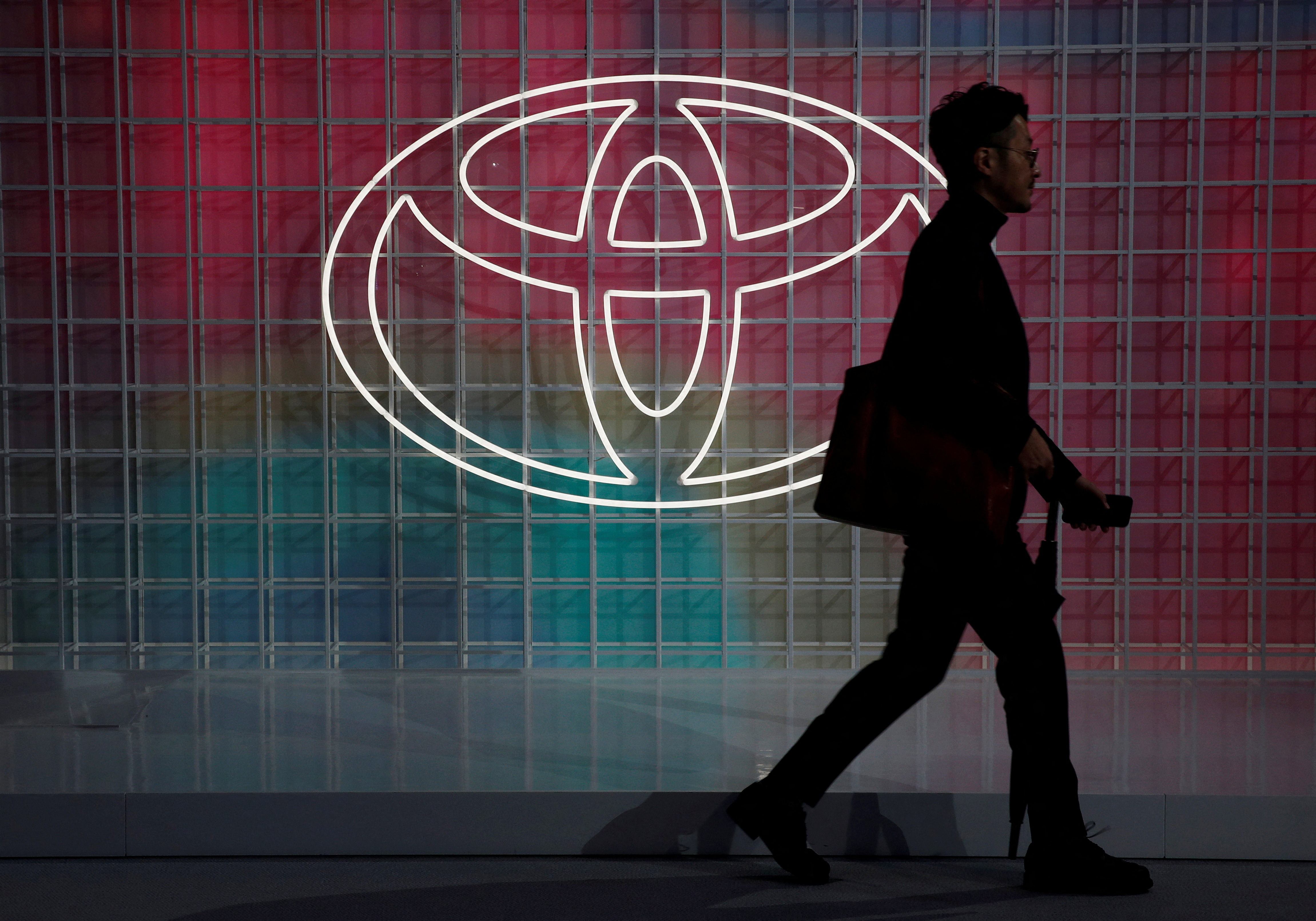 FILE PHOTO: A man walks past a Toyota logo at the Tokyo Motor Show, in Tokyo, Japan October 24, 2019. 