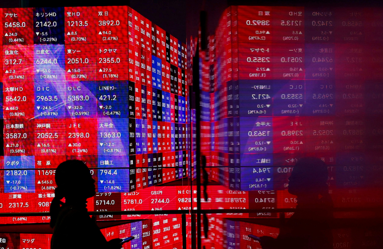 A visitor stands next to an electronic screen displaying Japan's Nikkei stock prices quotation board, inside a building in Tokyo, Japan on Feb. 22, 2024.