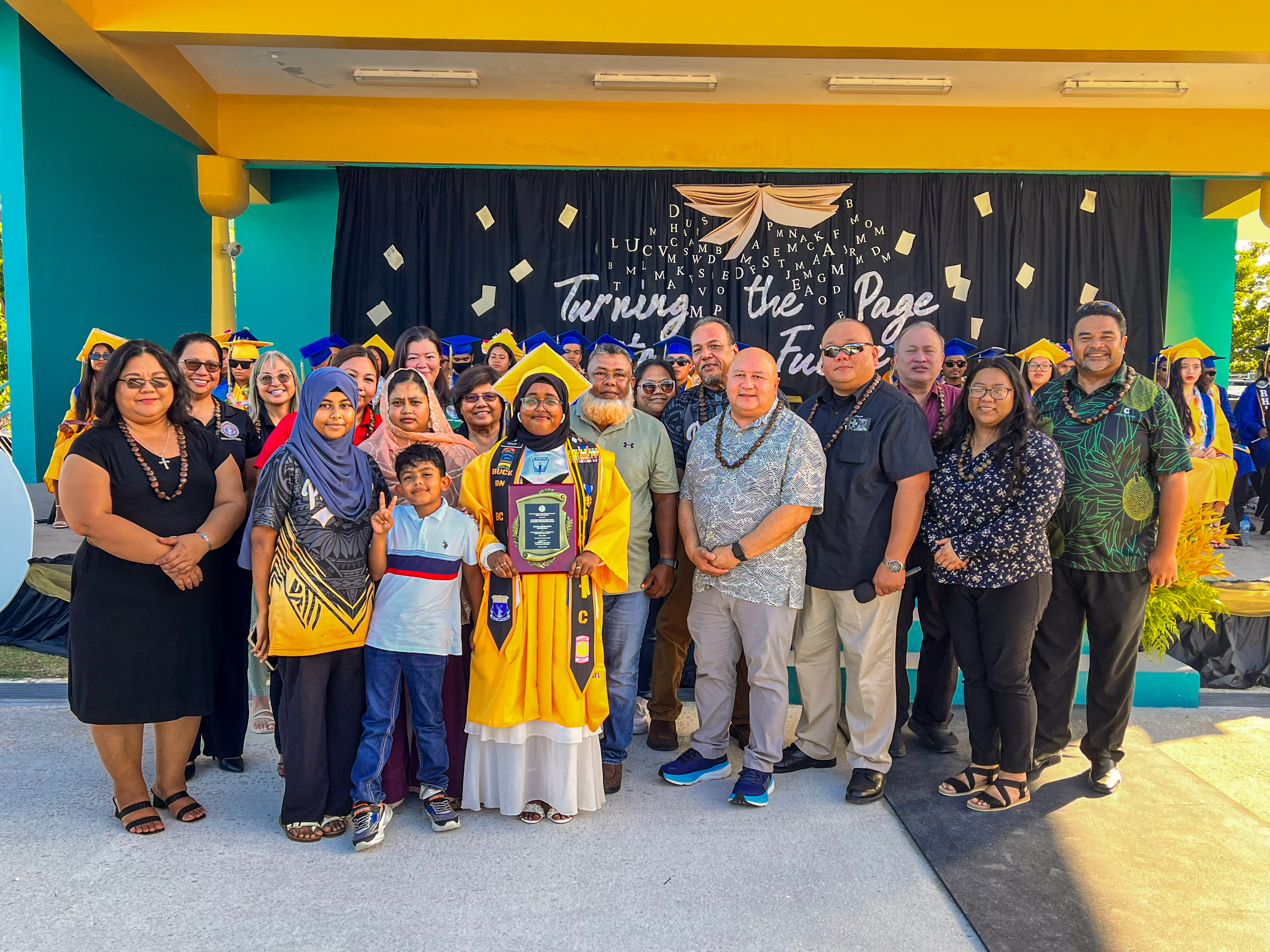 Class salutatorian Sayera Akter Sidur received the Commissioner of Education Academic Excellence Award from Commissioner of Education Dr. Lawrence F. Camacho. Also in photo are Associate Commissioner for Administrative Services Eric Magofna, Federal Programs Officer Jacqueline Che, and Senior Director for Accountability, Research, and Evaluation Jackie Quitugua, Instructional Technology and Distance Education Program Director Dr. Lorraine Catienza, Head Start/Early Head Start Director Lathania Angui, and Board of Education members.